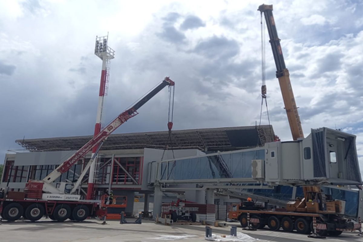 Passenger boarding bridge installed at an airport with two cranes